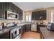 Modern kitchen featuring stainless steel appliances, dark cabinetry, and hardwood floors at 1386 Avgare Way, Erie, CO 80516