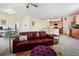 Cozy living room featuring a large red leather couch with a view into the kitchen and dining area at 1799 Jade Ave, Brighton, CO 80603