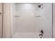 Elegant shower featuring white marble-style tiling and glass shelving at 1926 S Yates St, Denver, CO 80219