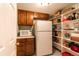 Well-organized pantry featuring shelving, cabinets, a microwave, and a full-size refrigerator at 3 Pinyon Pine Rd, Littleton, CO 80127