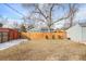 Large backyard with a wood fence, lawn, and mature trees at 2565 Pierce St, Lakewood, CO 80214