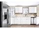 Bright kitchen featuring white cabinets, stainless steel appliances, and a stylish faucet with floral curtains at 2565 Pierce St, Lakewood, CO 80214