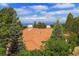 A view of the home's roof amid lush greenery with stunning mountain views in the background at 392 Starmine Pl, Castle Rock, CO 80108