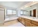 Bright primary bathroom featuring double sinks, a large mirror, soaking tub, and walk-in shower at 13515 Milwaukee Ct, Thornton, CO 80241