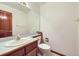 Powder room with a wood vanity, single sink, and large mirror at 13515 Milwaukee Ct, Thornton, CO 80241