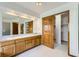 Bathroom featuring double sinks with wood cabinets, large mirrors, and a walk-in closet at 13515 Milwaukee Ct, Thornton, CO 80241