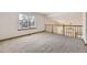 Spacious carpeted loft area with a large window and wooden banister at 13515 Milwaukee Ct, Thornton, CO 80241