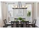 Elegant dining room with a modern chandelier, dark wood table, and abundant natural light from the surrounding windows at 2857 Xanthia Ct, Denver, CO 80238