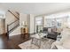 Bright living room featuring hardwood floors, a staircase, and an open layout flowing into other living spaces at 2857 Xanthia Ct, Denver, CO 80238
