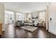 Comfortable living room showcasing dark hardwood floors, neutral decor, and ample natural light through large windows at 2857 Xanthia Ct, Denver, CO 80238