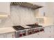 Close-up of a Wolf range stove in the kitchen with white cabinets and marble backsplash at 2821 E Cedar Ave # 14, Denver, CO 80209