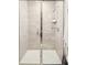 Elegant bathroom shower with glass doors, neutral tile, and modern fixtures and hardware at 3198 Blake St # 402, Denver, CO 80205