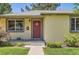 Close-up view of a home's inviting red front door and well-kept landscaping at 4111 S Delaware St, Englewood, CO 80110