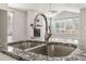 Close-up of a stainless steel kitchen sink with granite countertops and a view to an open-concept living space at 11482 Colony Loop, Parker, CO 80138