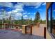 Large back deck with stone pillars and railings overlooks treed landscape with outdoor fireplace at 11405 Conifer Ridge Dr, Conifer, CO 80433