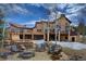 Luxury home featuring an outdoor kitchen, stone patio, and a built-in fireplace overlooking a beautiful yard at 11405 Conifer Ridge Dr, Conifer, CO 80433