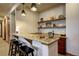 Home wet bar with granite countertops, bar stools, open shelves and custom cabinets at 11405 Conifer Ridge Dr, Conifer, CO 80433