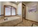 Serene bathroom with soaking tub nestled beneath a window with wood trim at 11405 Conifer Ridge Dr, Conifer, CO 80433