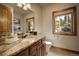 Bathroom with granite countertops, wood trim, and a window with a view of the forest at 11405 Conifer Ridge Dr, Conifer, CO 80433