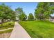 Lush green space with mature trees and a sidewalk, creating a serene and inviting outdoor environment at 10700 Kimblewyck Cir # 155, Northglenn, CO 80233