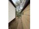 Narrow side yard showing beige and white vinyl siding on the house and shed with a walkway and trees overhead at 2625 W Ellsworth Ave, Denver, CO 80219