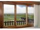 Expansive mountain views through a large window overlooking a fenced yard and barn at 2117 Stonehenge Cir, Lafayette, CO 80026