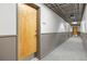 Well-lit hallway with carpet flooring, leading to a wooden apartment door at 1475 Delgany St # 306, Denver, CO 80202