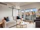 Bright living room with a barn door, hardwood floors, a comfortable sofa and a balcony with city views at 1475 Delgany St # 306, Denver, CO 80202