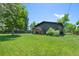 Exterior view of the home showcasing a large backyard, deck, and mature trees at 5265 W Quarles Dr, Littleton, CO 80128