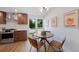 Bright eat-in kitchen features stainless steel appliances and a modern light fixture over a round table at 5265 W Quarles Dr, Littleton, CO 80128
