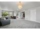 Bright living room with a chandelier, neutral walls, large windows, and open access to home office at 13802 Jasmine St, Thornton, CO 80602
