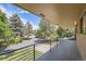 Covered porch with black railings featuring a view of the front yard and American flag at 12196 W Belleview Dr, Littleton, CO 80127