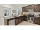 Lovely kitchen features stainless steel appliances, island with sink, and dark wood cabinetry at 309 Spruce St, Bennett, CO 80102