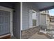 Close-up of the front porch, with a blue painted door, white trim, and decorative stone accents at 309 Spruce St, Bennett, CO 80102