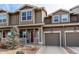 Inviting townhouse with a red front door, attached garage, and a small, gravel-covered front yard and covered porch at 256 Ash St, Bennett, CO 80102