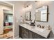 Bathroom featuring dual sinks, framed mirrors, modern lighting fixtures, and a view into the adjacent bedroom at 13 Club Ln, Littleton, CO 80123