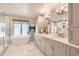 An elegant bathroom featuring marble tile, a soaking tub under a bright window, and a double sink vanity at 13 Club Ln, Littleton, CO 80123