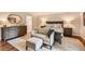 Bright bedroom featuring an upholstered chair, a wood dresser with mirror, and a doorway to the bathroom at 13 Club Ln, Littleton, CO 80123