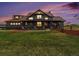 Charming craftsman style home with a covered front porch, green lawn, and mature landscaping under a colorful twilight sky at 1660 Prominence Cir, Elizabeth, CO 80107