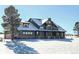 Inviting two-story home with a snow-covered yard, with a large tree in the front at 1660 Prominence Cir, Elizabeth, CO 80107