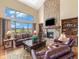 Elegant living room boasts a stone fireplace, vaulted ceilings, and a wall of windows with beautiful pastoral views at 1660 Prominence Cir, Elizabeth, CO 80107