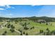 Scenic aerial shot of homes nestled in a green, hilly landscape under a bright blue sky with scattered clouds at 6880 Kilimanjaro Dr, Evergreen, CO 80439