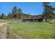 Well-maintained barn with fenced area, set in a lush field with trees, offering a serene rural ambiance at 6880 Kilimanjaro Dr, Evergreen, CO 80439