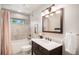 Updated bathroom with vanity, granite counters, shower and tub combo at 6880 Kilimanjaro Dr, Evergreen, CO 80439