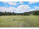 Picturesque open green field featuring scattered trees with mountains in the background at 6880 Kilimanjaro Dr, Evergreen, CO 80439