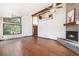 Expansive living room features a stone fireplace, wood floors, and large windows with wooded views at 6880 Kilimanjaro Dr, Evergreen, CO 80439