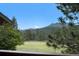 Scenic backyard view from the property featuring a green field and majestic mountains at 6880 Kilimanjaro Dr, Evergreen, CO 80439