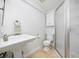 Clean and functional bathroom featuring a pedestal sink, toilet, cabinet, and glass-enclosed shower at 7082 W Morraine Dr, Littleton, CO 80128