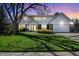Beautiful two-story home with a lush green lawn, mature trees, and attractive curb appeal at twilight at 7082 W Morraine Dr, Littleton, CO 80128