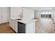 Modern kitchen island featuring a sink and dishwasher, with a view of the spacious living area at 19110 E 96Th Pl, Commerce City, CO 80022